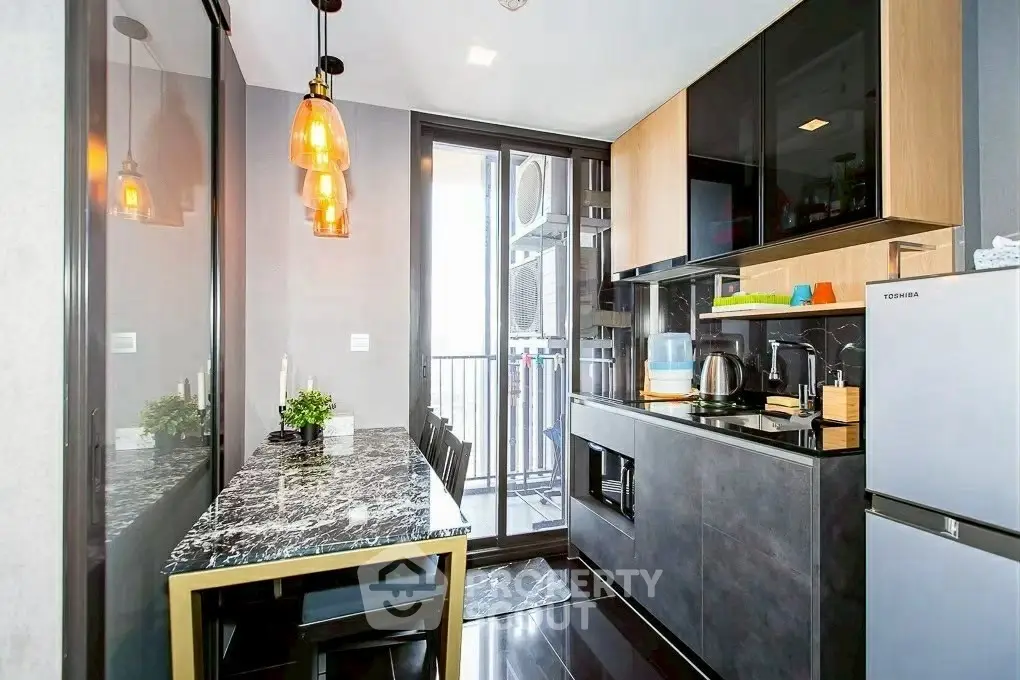 Modern kitchen with sleek design, marble dining table, and balcony access.