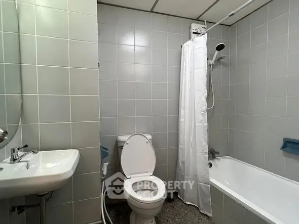 Modern bathroom with bathtub and shower in sleek tiled design.