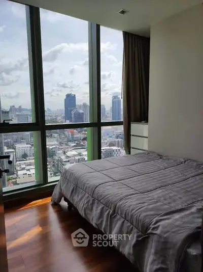 Modern bedroom with floor-to-ceiling windows offering stunning city views.