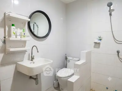 Modern bathroom with sleek fixtures and minimalist design, featuring a round mirror and wall-mounted sink.