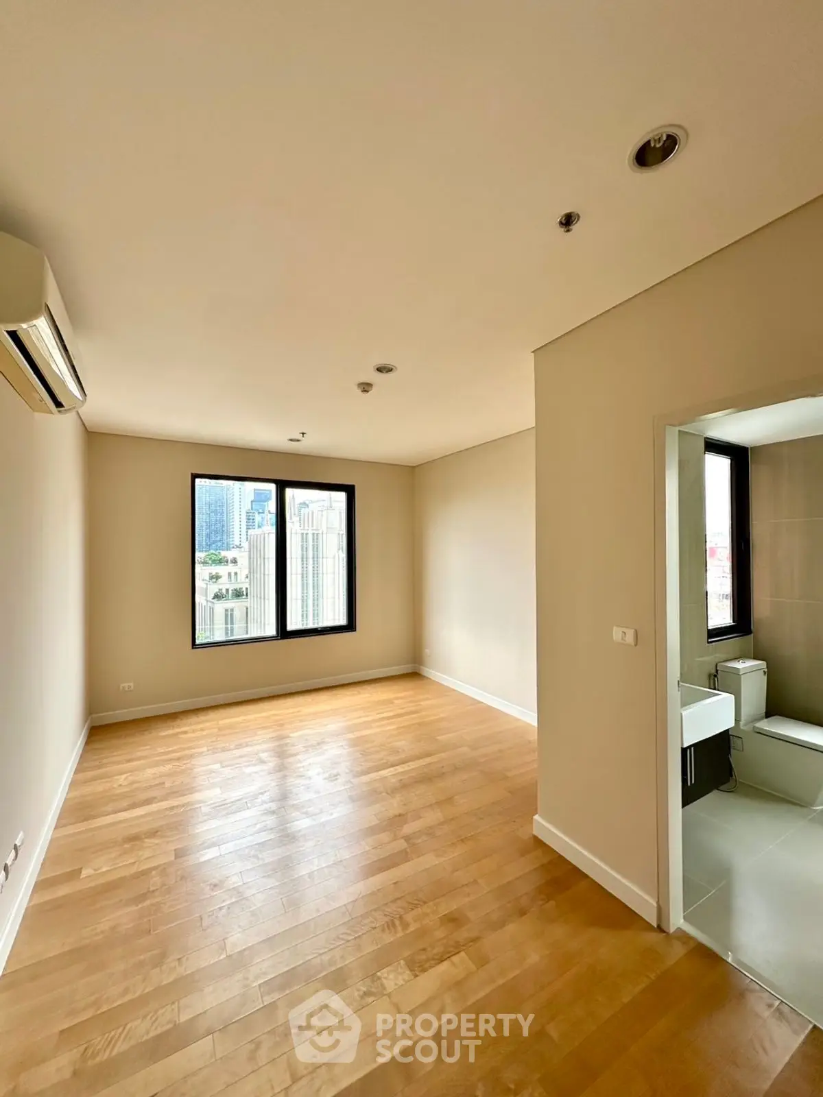 Spacious empty room with wooden floors and city view, ideal for customization.