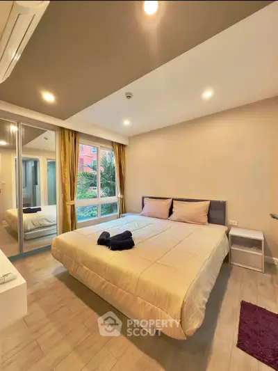 Modern bedroom with large window and mirrored closet doors in a cozy apartment.