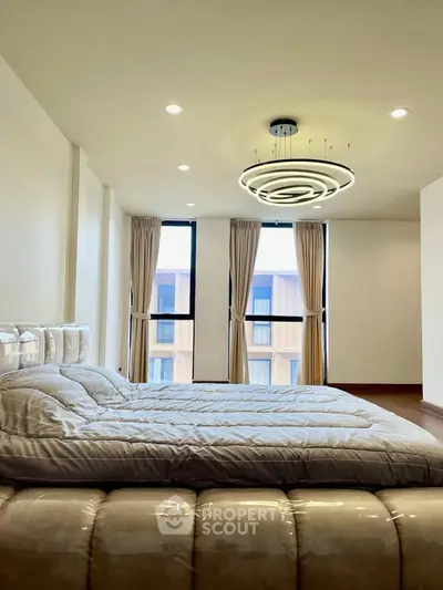 Spacious bedroom with modern lighting and large windows in a luxury apartment.