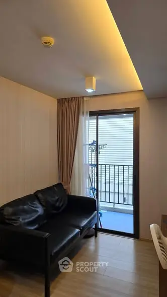 Cozy living room with black leather sofa and balcony access