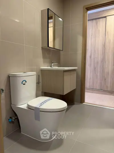 Modern bathroom with sleek fixtures and neutral tones, featuring a stylish vanity and toilet.
