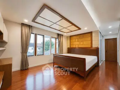 Spacious bedroom with wooden flooring and large windows offering natural light.