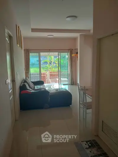 Spacious living room with large windows leading to a balcony, offering abundant natural light and a cozy seating area.