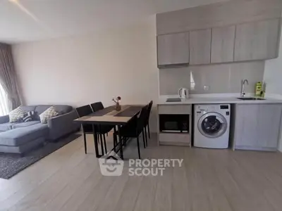 Modern open-plan living room with kitchen featuring sleek appliances and cozy seating area.