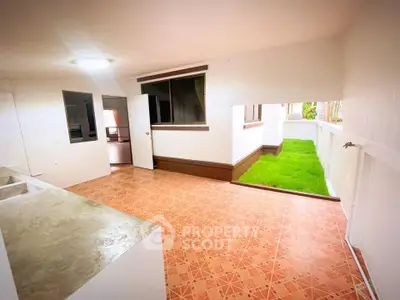 Spacious indoor-outdoor area with tiled flooring and small grassy patch, perfect for relaxation.