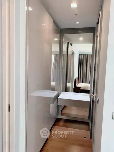 Modern hallway with sleek design and wooden flooring leading to a cozy bedroom.
