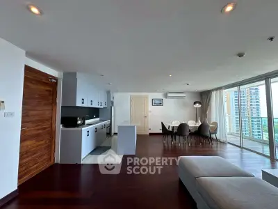 Spacious open-plan living room with modern kitchen and dining area, featuring large windows and city views.