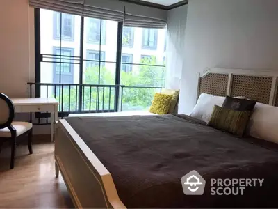 Spacious bedroom with large windows, modern furniture, and access to a private balcony in a contemporary urban residence.