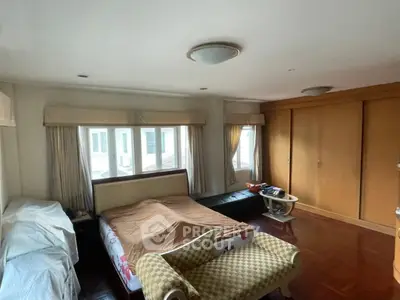 Spacious bedroom with large windows and elegant furnishings in a cozy real estate property.