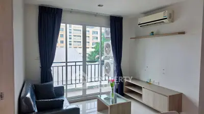 Modern living room with balcony view, featuring sleek furniture and air conditioning.
