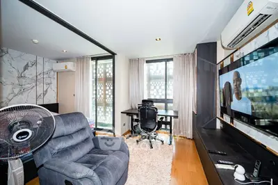 Modern living room with stylish decor, featuring a comfortable recliner, desk, and large TV, perfect for relaxation.
