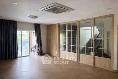 Spacious living room with wooden flooring and sliding glass doors leading to a balcony.