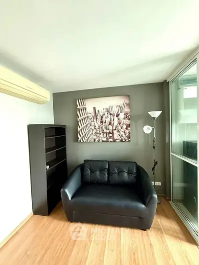 Modern living room with sleek black sofa and cityscape artwork, perfect for urban living.