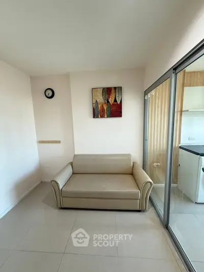 Cozy small living area with modern sofa and wall art, adjacent to glass sliding doors.