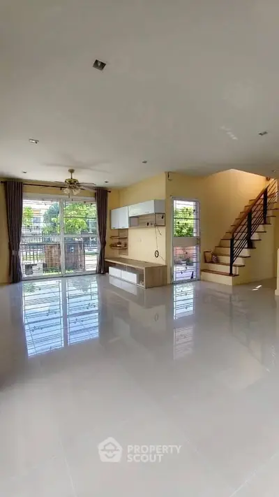 Spacious modern living room with large windows and staircase