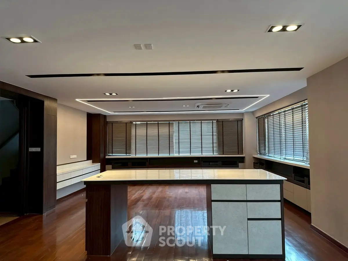 Spacious modern living room with elegant wooden flooring and large windows.