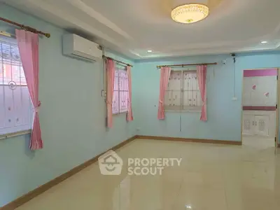 Spacious living room with elegant ceiling light and air conditioning, featuring pastel walls and tiled flooring.