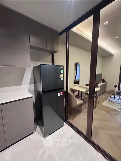 Modern kitchen with sleek design and glass partition leading to stylish living area.