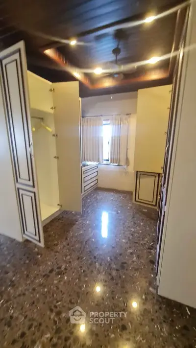 Spacious walk-in closet with elegant cabinetry and polished stone flooring