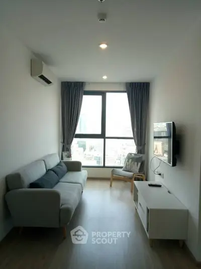 Modern living room with large window and city view, featuring a cozy sofa and wall-mounted TV.