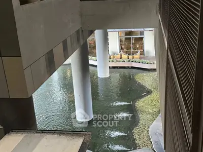 Modern architectural design with water feature and columns in urban setting.
