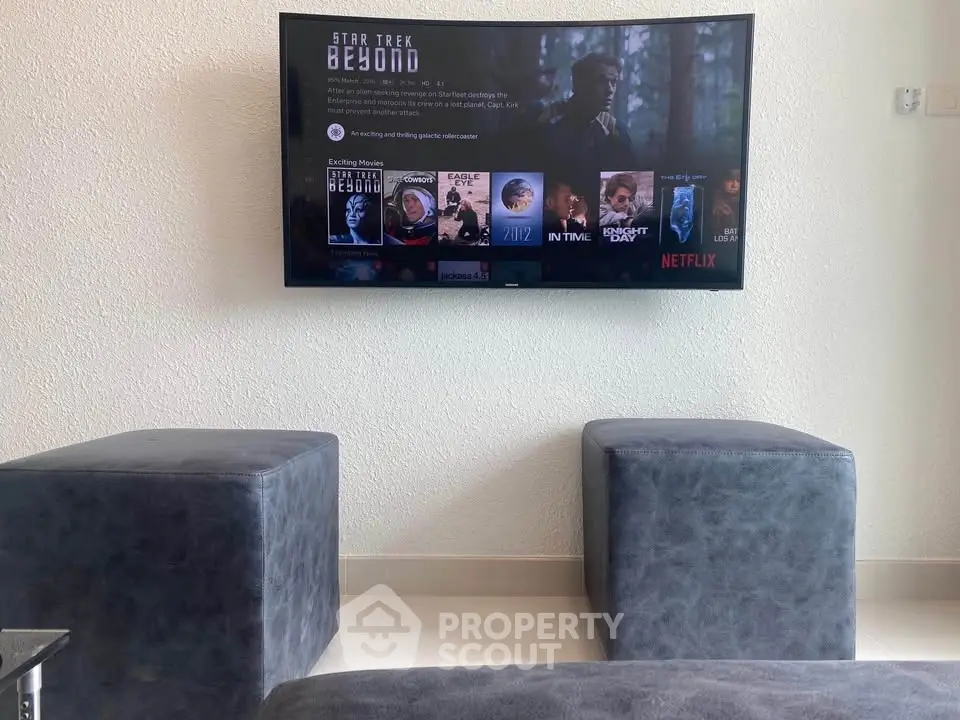 Modern living room with wall-mounted TV and stylish seating, perfect for entertainment.