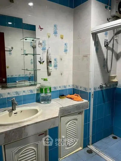 Charming bathroom with blue and white tiles, featuring a shower and vanity area.