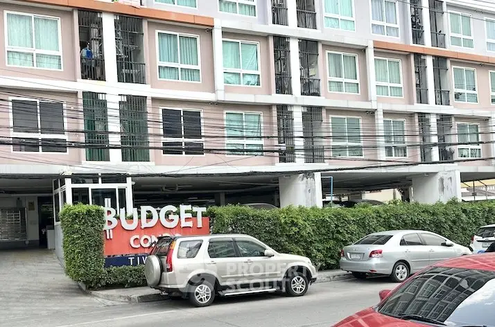 Modern budget condominium exterior with parking area and lush greenery