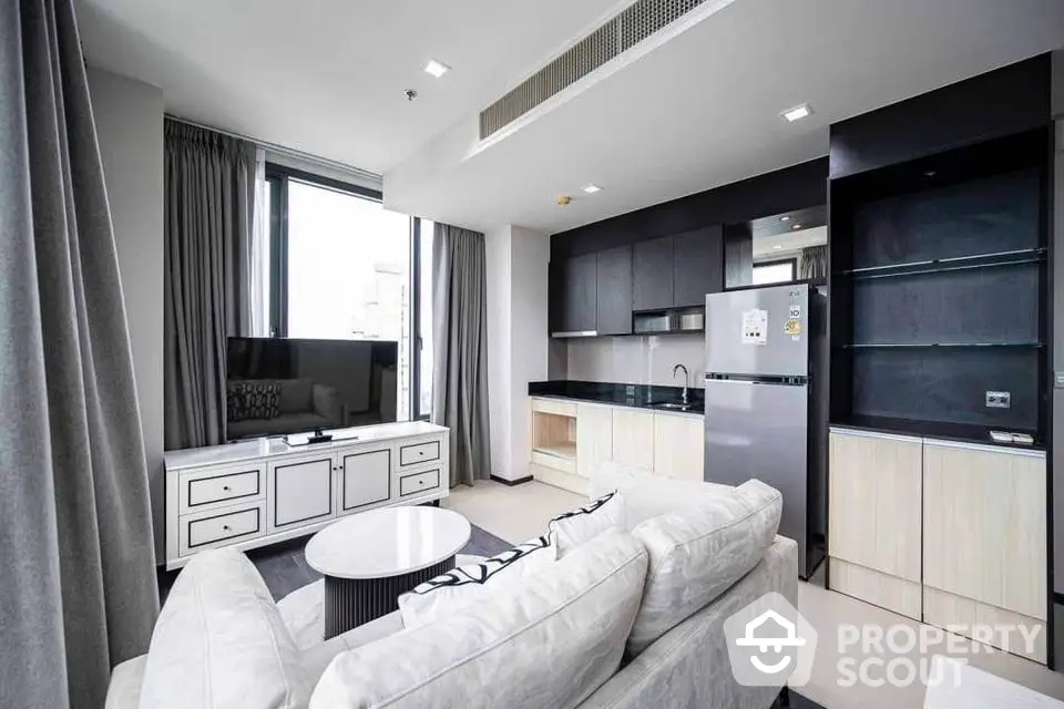 Modern living room with sleek furniture and open kitchen layout in luxury apartment.