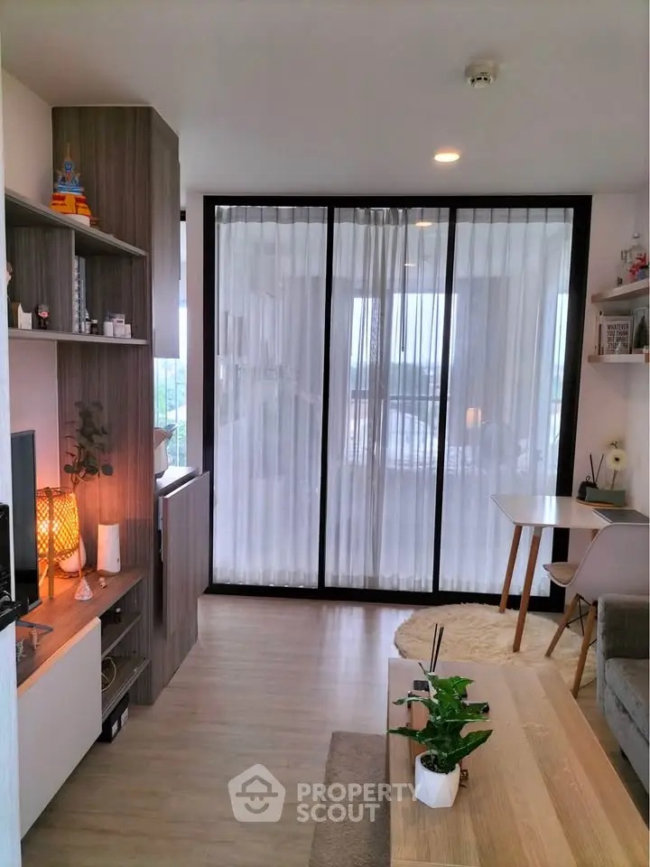 Modern living room with stylish decor and floor-to-ceiling windows offering natural light and a cozy ambiance.