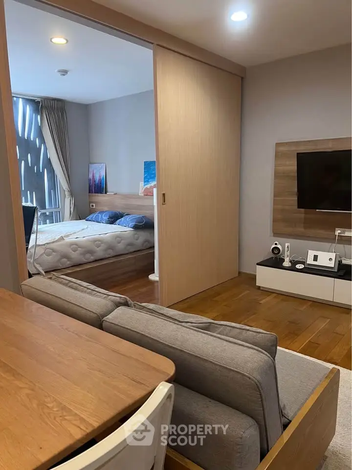 Modern studio apartment with cozy living area and bedroom, featuring wooden flooring and stylish decor.