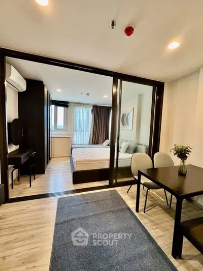 Modern studio apartment with glass partition, stylish dining area, and cozy bedroom.