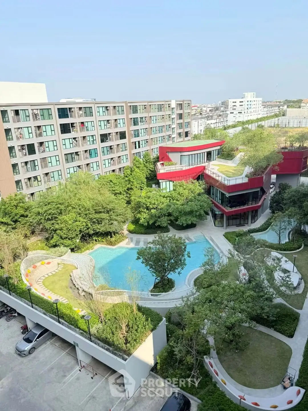 Stunning aerial view of modern apartment complex with lush gardens and inviting pool area.