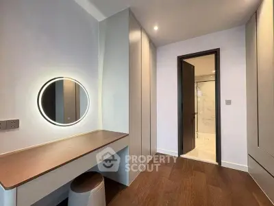 Modern bedroom with sleek vanity and ensuite bathroom, featuring elegant wood flooring and ambient lighting.