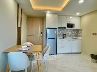 Modern kitchen with dining area, sleek cabinets, and stylish lighting in a cozy apartment.