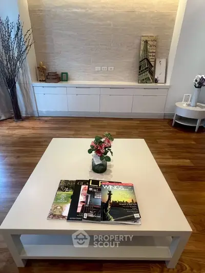 Stylish living room with elegant decor and wooden flooring, featuring a modern coffee table and magazines.