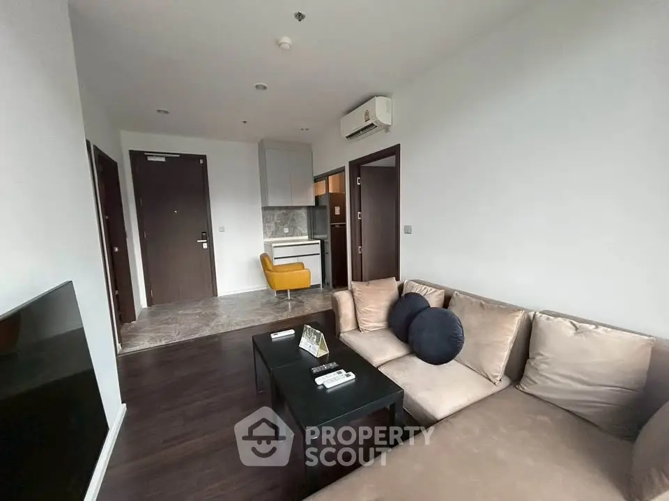 Modern living room with cozy sofa and open kitchen layout in stylish apartment.