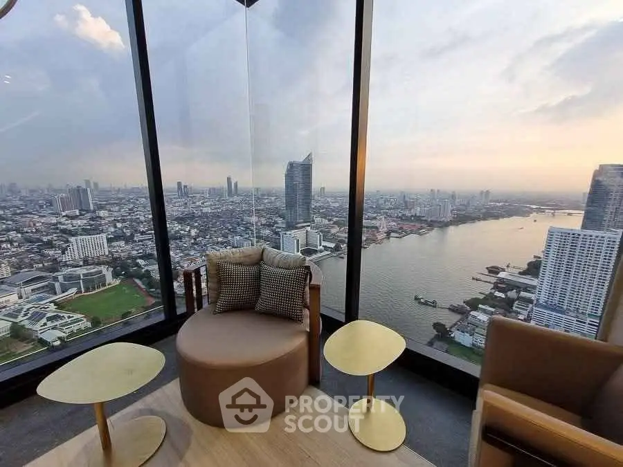 Stunning high-rise apartment with panoramic city and river views, featuring modern seating area and floor-to-ceiling windows.