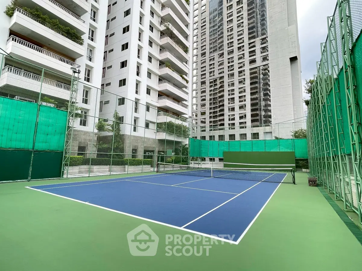 Spacious tennis court in modern residential complex with high-rise buildings