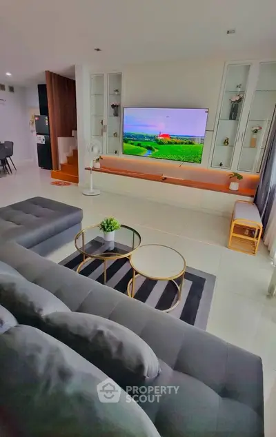 Modern living room with sleek furniture and large TV, perfect for relaxation and entertainment.