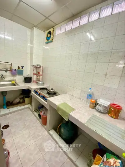 Cozy kitchen with tiled walls and gas stove, perfect for home cooking enthusiasts.