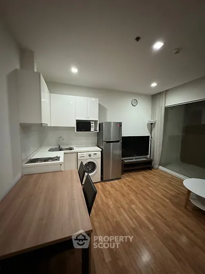 Modern studio apartment with integrated living space, featuring a sleek kitchen with stainless steel appliances, ample natural light, and a cozy dining area.