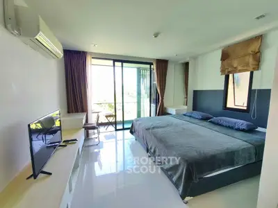 Spacious bedroom with large windows and balcony access, featuring modern furnishings and natural light.