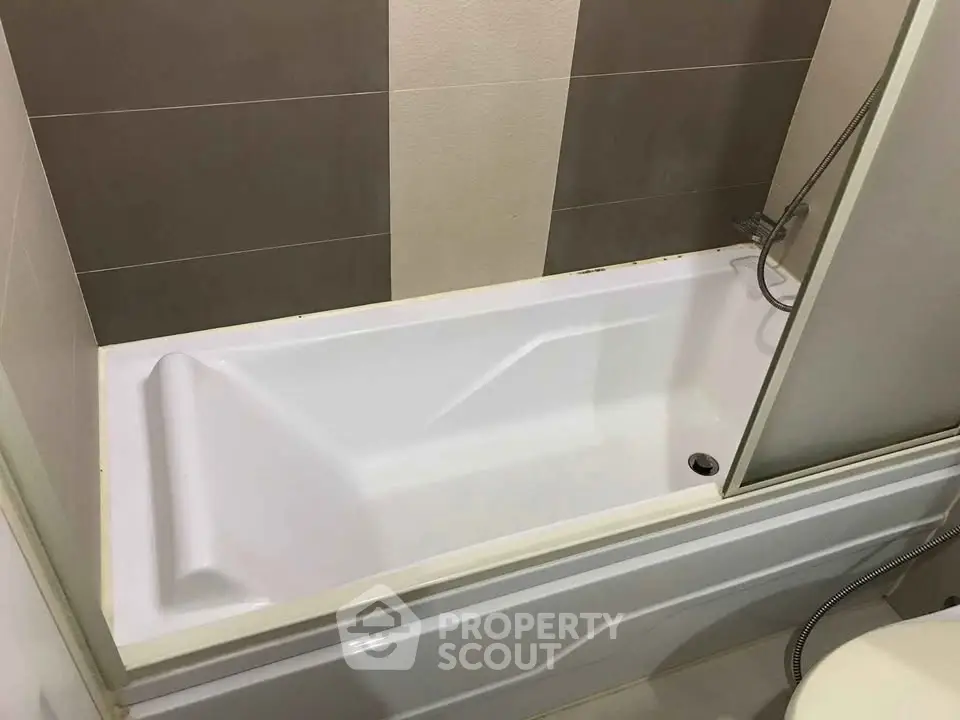 Modern bathroom with sleek bathtub and neutral tile design.