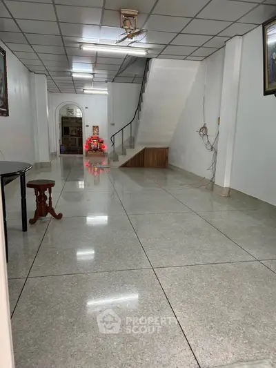 Spacious interior with glossy tiled floors and staircase, ideal for versatile living space.