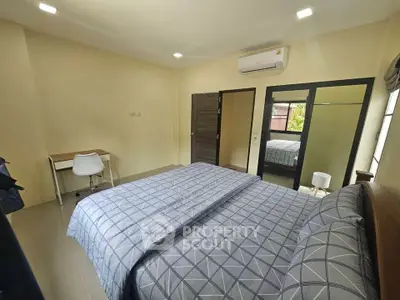 Spacious bedroom with modern decor and ample natural light, featuring a comfortable bed and study area.